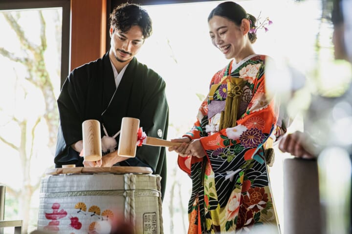 鏡開きをする引き振袖の新婦と羽織袴の新郎